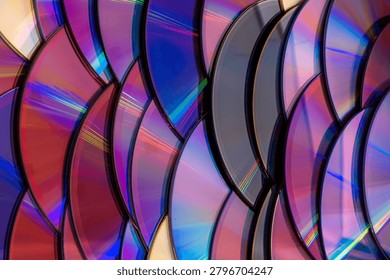 a dense, overlapping pattern of compact discs with rainbow light reflection arranged like fish scales