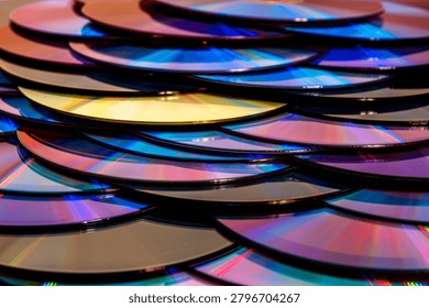 a dense, overlapping pattern of compact discs with rainbow light reflection arranged like fish scales