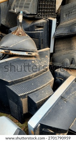 Dense pile of discarded, obsolete Cathode Ray Tube (CRT) televisions and monitor casings covered in dust and dirt, symbolizing electronic waste (e-waste) and environmental pollution.
