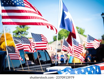 Dense of Texas and American flags on cargo bed of modern pickup truck driving on residential street smalltown Fourth of July parade, Dallas, Texas, USA blurry diverse people. Independence Day patriot - Powered by Shutterstock