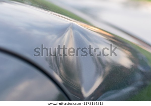 Dent on the car. Concavity on the frame of the\
car. Road accident.
