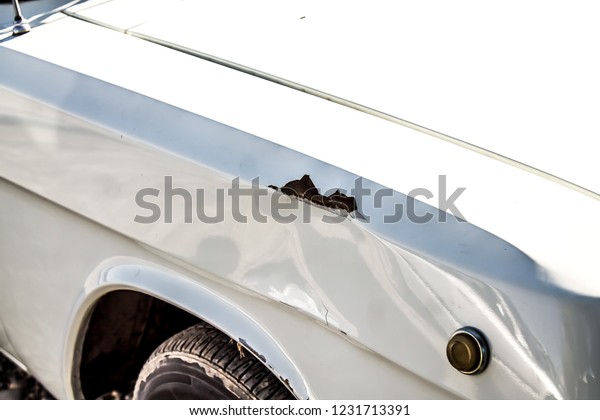 Dent and scratch on the\
wing of a car