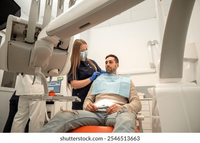 Dental assistant adjusting the patient’s bib before treatment in the clinic - Powered by Shutterstock