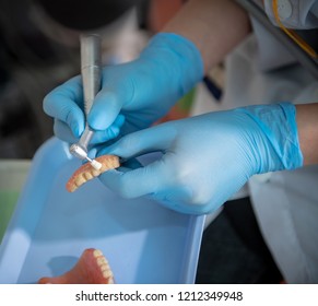 dental assistant cleaning dentures by hand wearing rubber gloves
