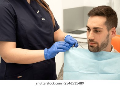 Dental assistant preparing the patient with a protective bib before the procedure - Powered by Shutterstock