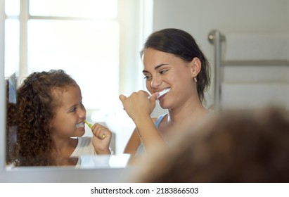 Dental care, brushing teeth and healthy routine in mother and daughter morning at home. Happy, fun and playful child and parent bonding and learning hygiene and grooming with toothpaste in a