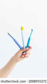 Dental Care Conept. Dentistry Tools. Three Blue Toothbrushes For Braces In A Woman Hand On White Background. Vertical Photo, Story Instagram With Copyspace.