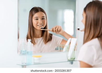 dental care, hygiene and people concept - happy smiling teenage girl with toothbrush brushing teeth at bathroom - Powered by Shutterstock