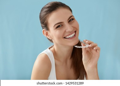 Dental care. Smiling woman with healthy teeth using removable clear braces aligner, orthodontic silicone trainer. Portrait girl with white smile using invisible whitening tray - Shutterstock ID 1429531289