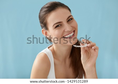 Dental care. Smiling woman with healthy teeth using removable clear braces aligner, orthodontic silicone trainer. Portrait girl with white smile using invisible whitening tray
