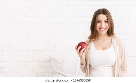 Dental Care. Young Pregnant Woman Enjoying Fresh Apple In Bed, Empty Space