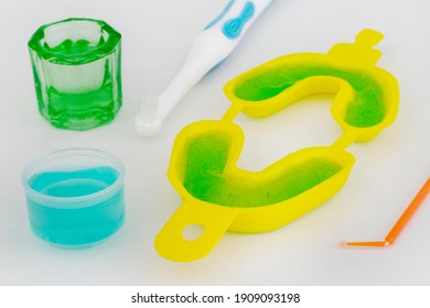 Dental Concept Of Teeth Care With Fluoride. Dental Tray With Fluoride Gel And Glass With Liquid Fluorine And A Cap With Clorhexidine With Brush And Microbrush To Apply. 