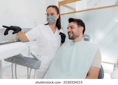 Dental consultation in a modern clinic with a dentist showing a patient the treatment plan - Powered by Shutterstock