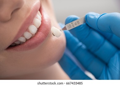 Dental crown situating near mouth of happy woman - Shutterstock ID 667433485