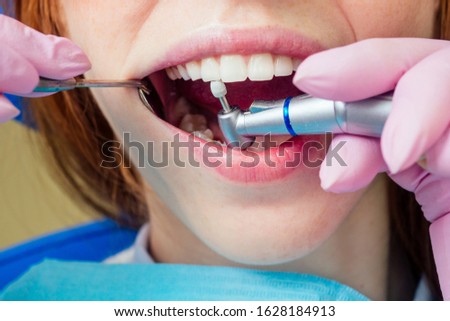 Dental drilling procedure and check up on beautiful teeth and open mouth