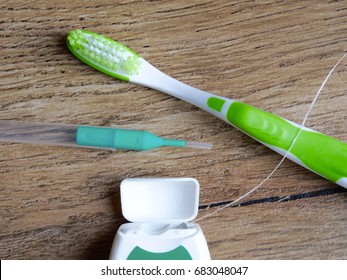 Dental Floss, Interdental Brush And Toothbrush On Wood Background