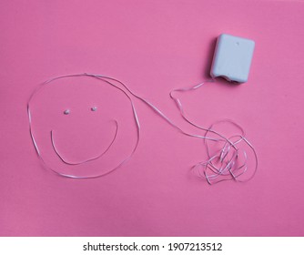 Dental floss in the shape of a happy face against a pink background - Shutterstock ID 1907213512