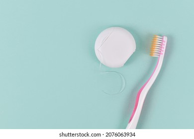 Dental Floss And Tooth Brush On Side Of Green Background With Copy Space