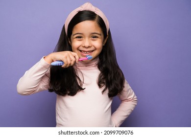 Dental hygiene. Cheerful girl enjoying brushing her teeth and smiling after eating breakfast - Powered by Shutterstock