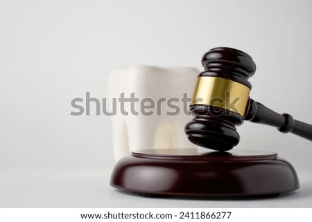 Dental insurance concept. White tooth and judge gavel. Forensic dentistry or forensic odontology concept