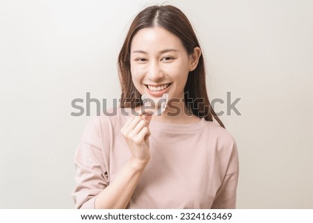Dental invisible braces, beautiful smiling asian young woman holding invisalign braces, wearing orthodontic silicone trainer, white smile using invisible whitening tray. Stomatology, dental healthcare [[stock_photo]] © 