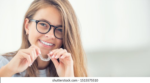 Zahnliche unsichtbare Klammern oder Silikon-Trainer in den Händen eines jungen lächelnden Mädchens. Orthodontisches Konzept - Invisalign.