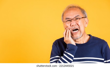 Dental Pain. Asian Unhappy Elder Man Problems With Gum Pain Studio Shot Isolated On Yellow Background, Portrait Senior Old Man Sad Hand Touching Cheek Suffering From Toothache, Dental Healthcare