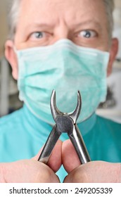 Dental Pliers In Hands Of Scary Dentist. Selective Focus On Pliers