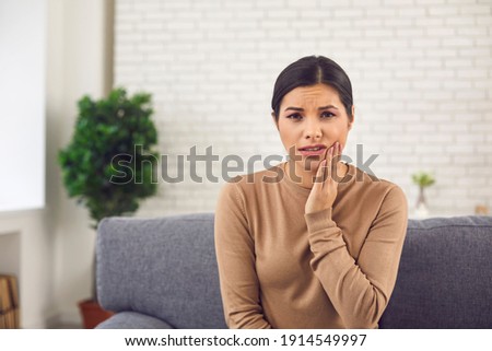 Dental problem concept. Portrait of young woman with acute toothache, inflamed nerve, or cheek swelling after tooth removal. Webcam head shot of sad female patient suffering from severe pain at home