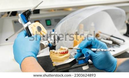 Dental prosthesis work. Denture work. Teeth painting. Dental technician working with tooth denture at prosthesis laboratory