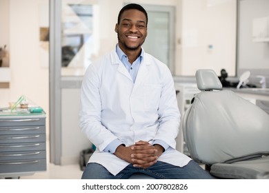 Dental Services. Professional Black Male Stomatologist Posing At Workplace In Clinic Interior, Happy African American Dentist Dentist Doctor In Uniform Smiling At Camera, Ready For Check Up