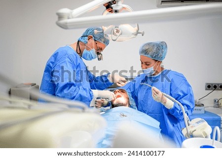 Dental surgeon and assistant work putting dental implant