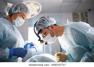 Dental surgery. The surgeon and the assistant. The patient is unrecognizable. Modern dentistry. Photo in the operating room. Concept of healthcare.
