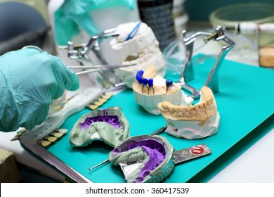 Dental Technician Checks His Work In The Lab