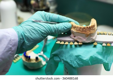 Dental technician checks his work in the lab - Shutterstock ID 360488168