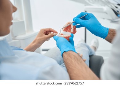 Dental technician using 3d teeth model to show to client problem places - Powered by Shutterstock