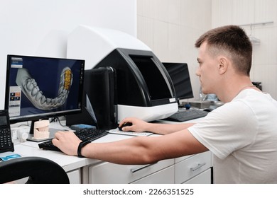 Dental technician working with a computer in a laboratory. 3D modeling of the crown in the dental lab. Workplace dental technician.