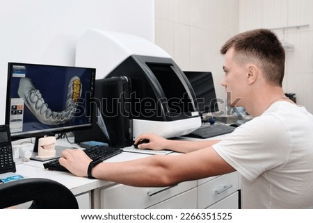 Dental technician working with a computer in a laboratory. 3D modeling of the crown in the dental lab. Workplace dental technician.