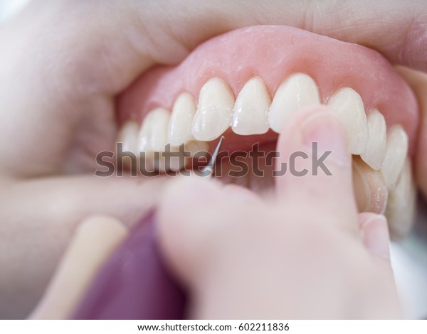 Dental technician is working with\
porcelain teeth in a cast molde in dental\
laboratory.