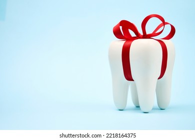 Dental treatment concept. Dental offers free treatment. White tooth model with red bow ribbon on a blue background with copy space, close-up - Shutterstock ID 2218164375