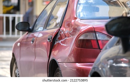 Dented car with damaged body parked on city street side. Road safety and vehicle insurance concept - Shutterstock ID 2122753895