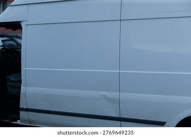Dented side panel of van closeup, metal crease and paint scuff detailed, reflection of apartment facade, focus on damage and repair needs, insurance documentation imagery potential