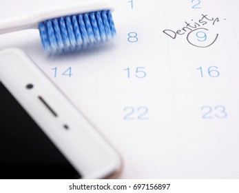 Dentist Appointment Reminder On Calendar With Tooth Brush And Mobile Phone ; Medical Concept