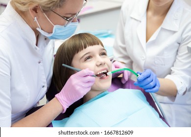Dentist and assistant examining kid mouth with dentistry equipment instrument. Teeth treatment for children. Stomatology and orthodontology