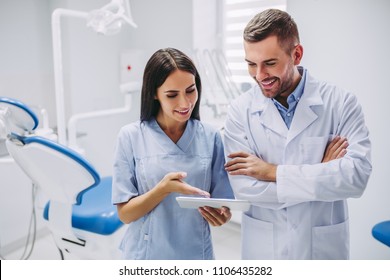 dentist and assistant looking at digital tablet screen in modern dental clinic - Powered by Shutterstock