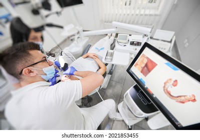 Dentist and assistant in medical masks using dental intraoral scanner while examining patient teeth in dental office. Intraoral scanning with modern scanning machine. Concept of digital dentistry. - Powered by Shutterstock