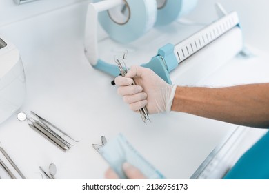 Dentist assistant sterilizing and packing dentist equipment in plastic sterilization pouches - Shutterstock ID 2136956173