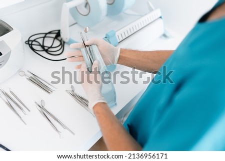 Dentist assistant sterilizing and packing dentist equipment in plastic sterilization pouches