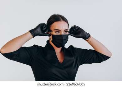 Dentist In A Black Coat Puts On A Protective Black Mask Against Covid