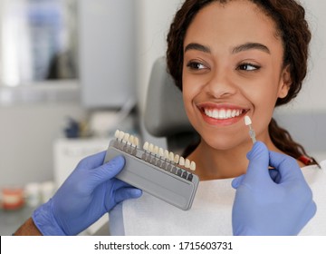 Dentist In Blue Medical Gloves Applying Sample From Tooth Enamel Scale To Happy Black Woman Patient Teeth, Close Up